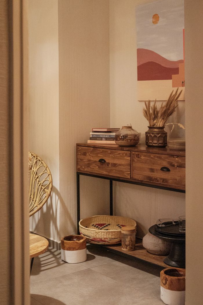 Stylish room interior featuring a wooden drawer, decorative vases, and books.